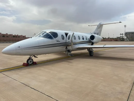 Charter-a ltd private jet parked on an airport tarmac under a cloudy sky.