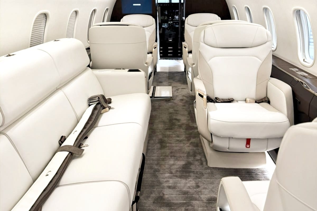 Cream leather seats and carpeted aisle inside a Bombardier Challenger 3500 cabin, typical of the aircraft on this flight
