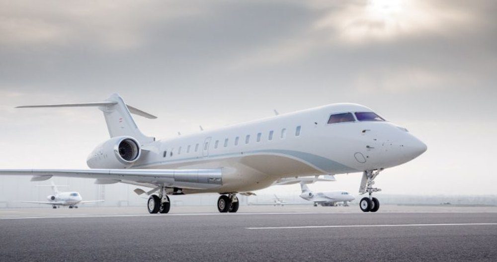 White private jet parked on the tarmac under an overcast sky